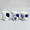 Three white porcelain cups with abstract splashes of cobalt blue
